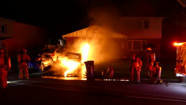 消防士が行動に出る間に車の火災が近くの家に損害を与え始め — ストック動画