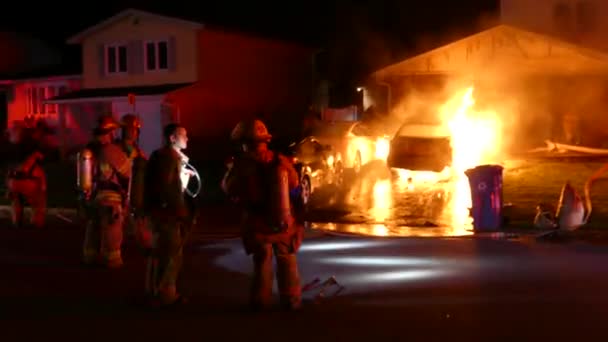 Brandmän Står Gatan Medan Kollegor Bekämpa Bilbrand Ett Hem Uppfart — Stockvideo