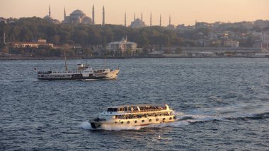 İstanbul Boğazı 'nda gün batımında İstanbul siluetine doğru yol alan banliyö teknesi, İstanbul, Türkiye - 27 Eylül 2012