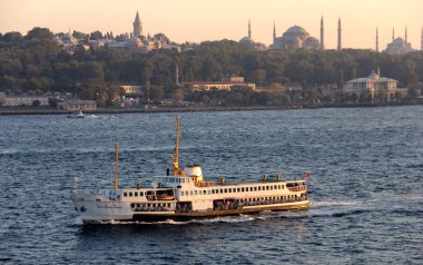 İstanbul Boğazı 'nda gün batımında İstanbul siluetine doğru yol alan banliyö teknesi, İstanbul, Türkiye - 27 Eylül 2012