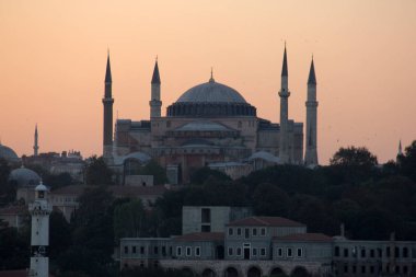 İstanbul silueti gün batımında bir kubbe ve Ayasofya minareleri ile gökyüzüne yükseliyor, Türkiye