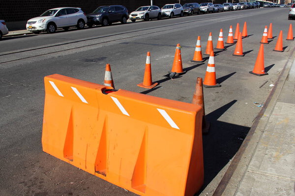 Orange plastic road barrier and traffic cones on a side of a street in Sunset Park, Brooklyn, NY, USA - February 22, 2020
