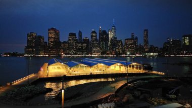 Brooklyn 'den East River' a uzanan Lower Manhattan siluetinin gece görüşü, Brooklyn tarafında halka açık atletizm sahaları ön cephede, New York, New York, ABD - 5 Nisan 2017