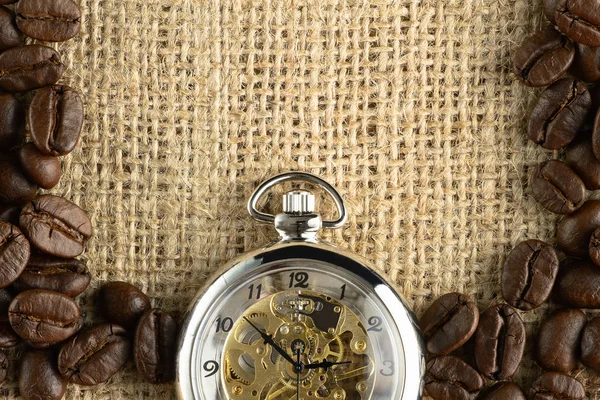 Coffee background of roasted coffee beans and pocket watch on gu — Zdjęcie stockowe