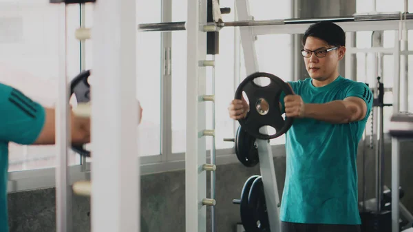 Aziatische man met bodybuilding met gewichtheffen in de sportschool of fitnessruimte — Stockfoto