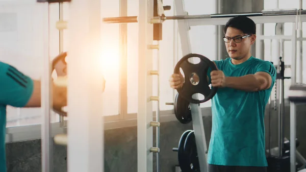 Aziatische man met bodybuilding met gewichtheffen in de sportschool of fitnessruimte — Stockfoto
