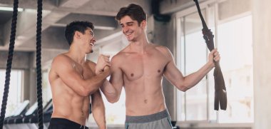 İki mutlu beyaz adam spor salonunda birlikte antrenman yapıyor.