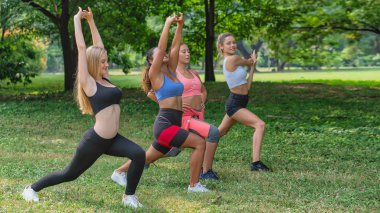 Bayan arkadaşlar parkta birlikte antrenman yapıyorlar.