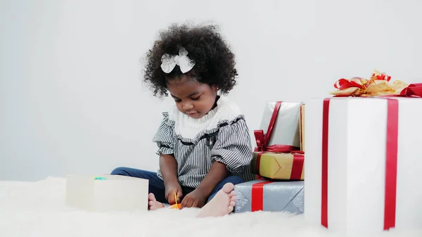 Black girl child playing toy from present box in white room — 스톡 사진