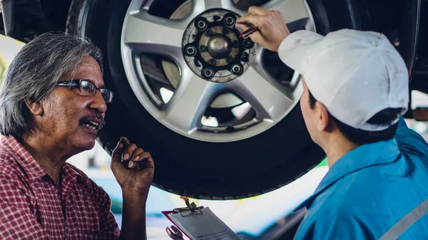 gargae customer and car mechanic together investigate maintenanc