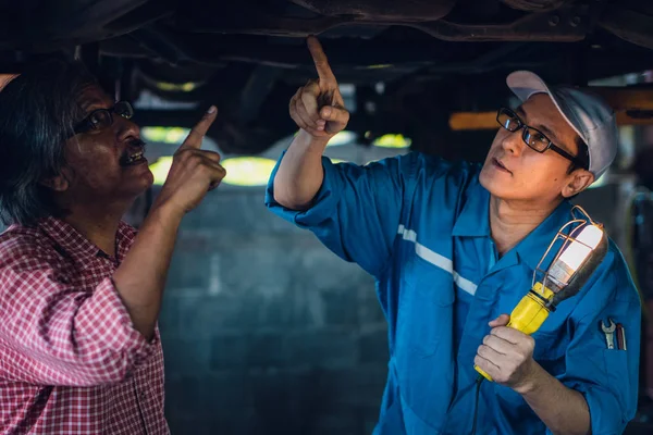 Gargae klient i mechanik samochodowy wspólnie zbadać utrzymanie — Zdjęcie stockowe