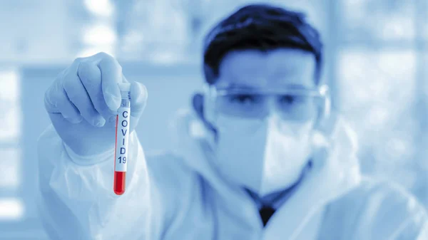 Coronavirus covid-19 laboratuardaki biyolojik tehlike koruma giysilerindeki bilim adamının elindeki örnek tüpte bulunan kan örneğini enfekte etti.