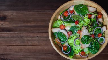 Sebze salatalarının arka planında ahşap masada tavuk eti var.