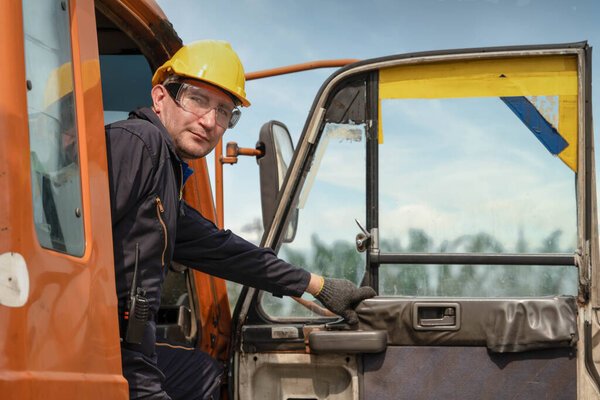 портрет водителя грузовика в желтом грузовике на стройке
