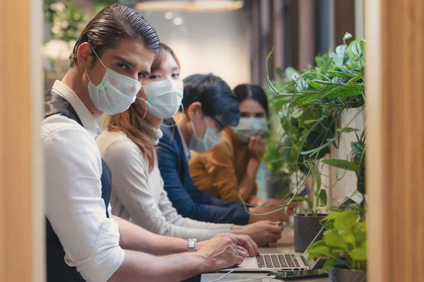 business people wearing medical mask for coronavirus covid 19 protection working together at coworking spaces, working safety in novel coronavirus covid 19 outbreak situation, selective focused