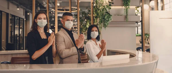Tıbbi maske takan otel resepsiyonisti ve Coronavirus covid 19 pandemik salgınında yeni bir karşılama pratiği yaptığı için Thai wai ile selamlaşma gösterisi yapıyor.