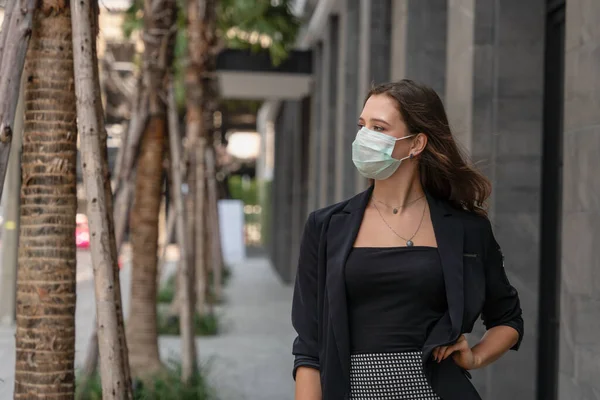 Coronavirus covid 19 korumasında tıbbi maske takan Kafkas iş kadınının iş geçmişi. Şehirde ofis binasının yanında duruyor, Coronavirus covid 19 salgın durumunda çalışıyor.