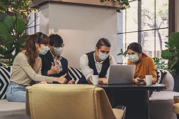 Kafkas ve Asyalı iş adamlarının iş ortaklığı lobisinde birlikte çalışmalarının iş geçmişi ve Coronavirus covid 19 enfeksiyonundan korunmak için maske takan herkes Coronavirus salgını durumunda çalışıyor.