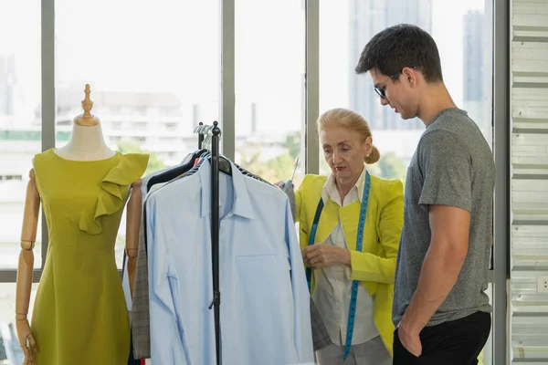 Female Senior Dressmaker Offer Her Design Clothes Young Male Customer — Stock fotografie