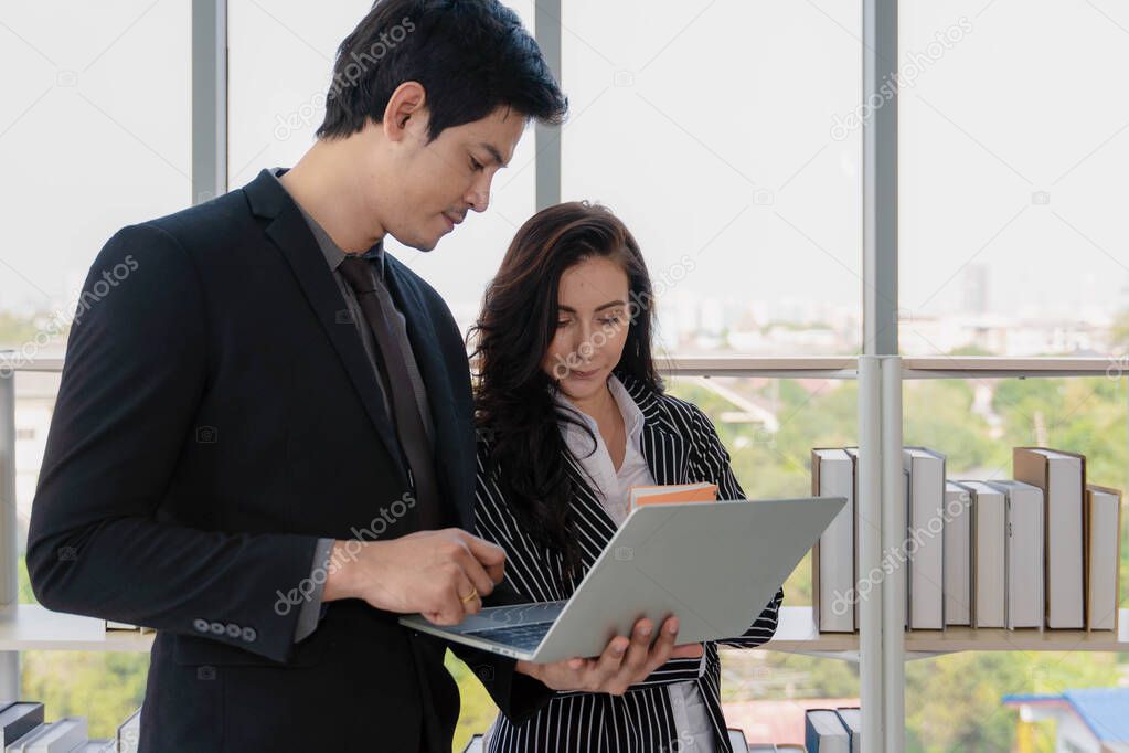 business background of diversity businesspeople of asian businessman and caucasian businesswoman having business discussion together with laptop and notebook on hands