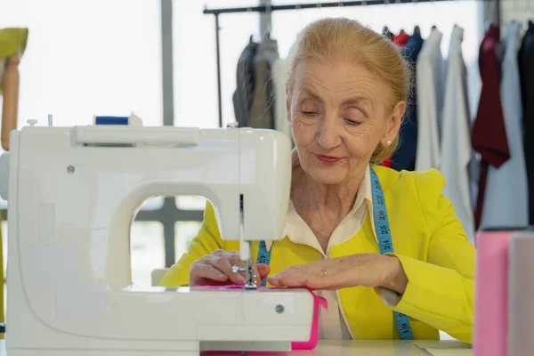 Vrouwelijke Senior Kleermaker Met Behulp Van Naaimachine Maken Jurk Bij — Stockfoto