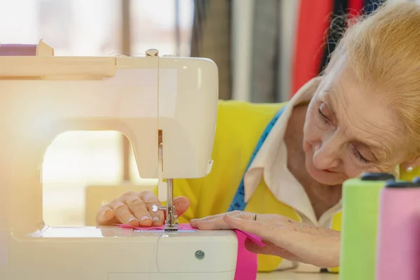 Vrouwelijke Senior Kleermaker Met Behulp Van Naaimachine Maken Jurk Bij — Stockfoto