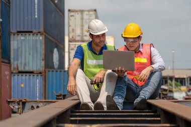 Kafkas konteynır avlusunun endüstriyel arka planı ve kargo yükleme denetleyicisi ve Asyalı müfettiş konteynır kamyonu üzerinde birlikte çalışıyorlar.