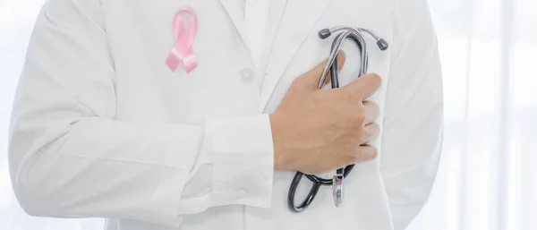 breast cancer awareness campaign background of doctor in lab coat with stethoscope having breast cancer awareness symbol of pink ribbon on white coat