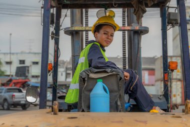 Afrika kökenli Amerikan forklift sürücüsü konteynır deposu ve kargo deposunda forklift kullanıyor.