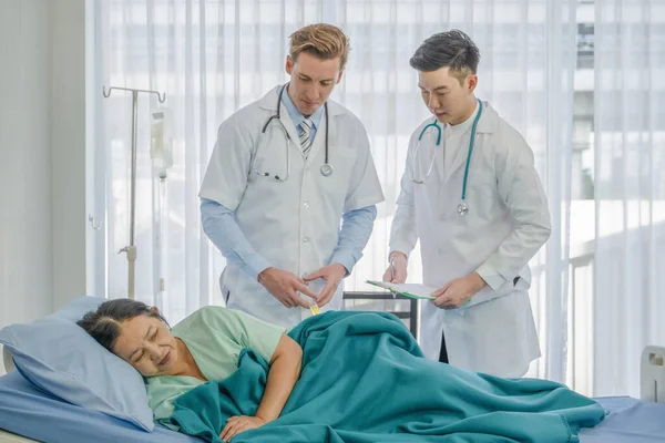 healthcare background of caucasian medical doctor make disease treatment for senior asian female patient lying on bed by antibiotic injection in hospital