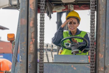 Afrika kökenli Amerikan forklift sürücüsü konteynır deposu ve kargo deposunda forklift kullanıyor.