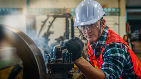 industrial background of caucasian mechanics engineer operating lathe machine for metalwork in metal work factory