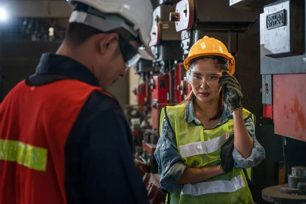 industrial background of new female mechanic engineer listening to asian male mechanic engineer supervisor that explaining machine work procedure to in metal work manufacturing factory