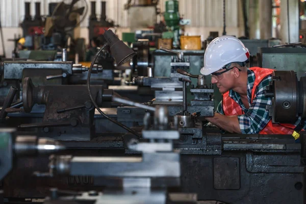 industrial background of caucasian mechanic engineer with lathe machine in metal work and machine part manufacturer workshop and factory for precision adjustment