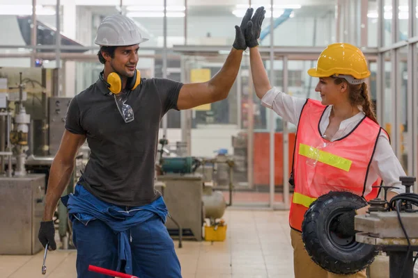 two factory workers having highfive together showing teamwork of success in metal work factory