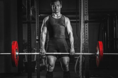 Asyalı atletik güçlü adam vücut geliştiriyor ve vücut geliştiriyor. Spor salonunda ağırlık kaldırma stili, spor salonunda spor salonu ve spor salonunda koyu tonda spor yapıyor.