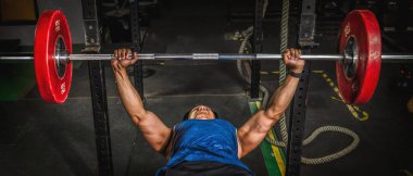 Asyalı güçlü atletik adam spor yapıyor ve vücut geliştiriyor. Spor salonunda ağırlık kaldırıyor ve spor salonunda koyu renk spor yapıyor.