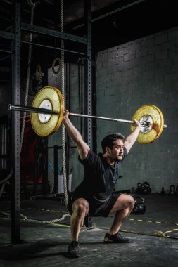 Asyalı güçlü atletik adam vücut geliştiriyor ve vücut geliştiriyor halterli ağırlık kaldırıyor beden eğitimi dersinde ve beden dersinde iki tonda.
