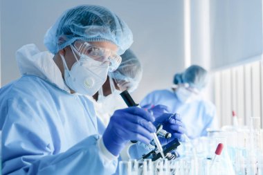 Coronavirus aşısı geliştirmek için mikroskopla çalışan biyokimyasal araştırma ekibi ilaç laboratuvarında çalışıyor.