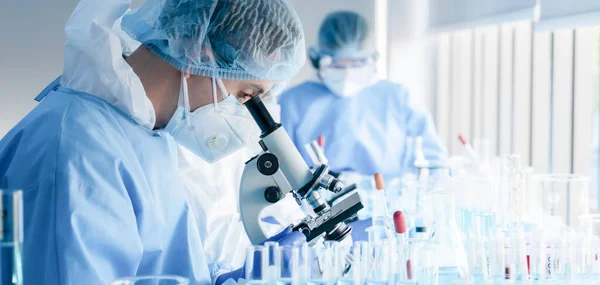 Coronavirus aşısı geliştirmek için mikroskopla çalışan biyokimyasal araştırma ekibi ilaç laboratuvarında çalışıyor.