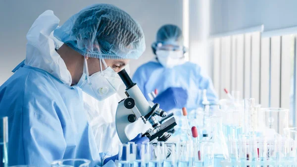 Coronavirus aşısı geliştirmek için mikroskopla çalışan biyokimyasal araştırma ekibi ilaç laboratuvarında çalışıyor.