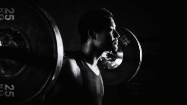 Asyalı güçlü atletik adam spor yapıyor ve vücut geliştiriyor halterlerle ağırlık kaldırıyor spor salonunda ve spor salonunda siyah beyaz tonda spor yapıyor.