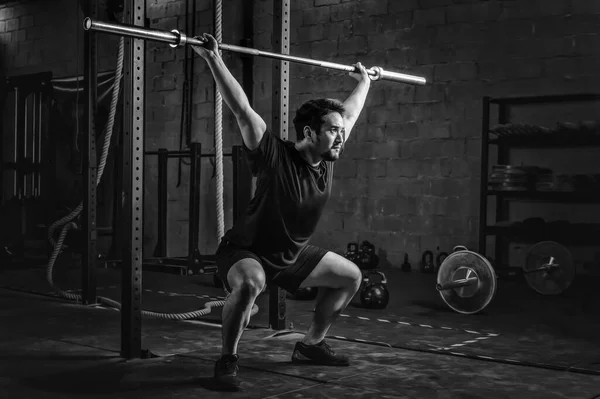 asian strong athletic man having workout and bodybuilding with barbells weight lift over head squat style in gym and fitness club in black and white