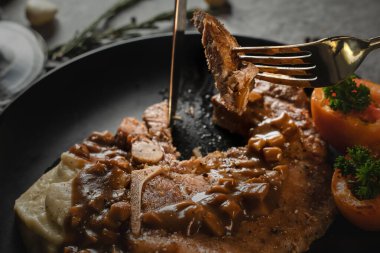 Domuz pirzolası soslu domuz pirzolası ve siyah patatesle servis edilen domuz pirzolasının yemek arkaplanı koyu tonda, seçici bir şekilde masada.