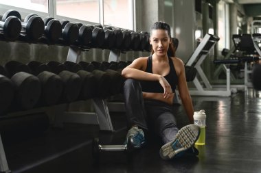 Beyaz kadın spor yaptıktan sonra dinleniyor ve spor ve spor salonunda egzersiz yapıyor. Sallanan dambıllar, sağlıklı spor kadın yaşam tarzı.