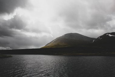 Bulutlu dağların önünde göl