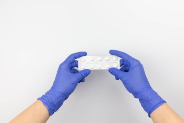 Ellerinde koruyucu eldivenler, ellerinde haplar.