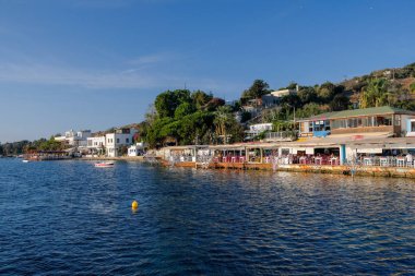 Gumusluk, Bodrum sahilindeki restoran ve bougainvillea çiçekleri. Güzel Ege Denizi yakınlarındaki Bodrum kasabasında renkli sandalyeler, masalar ve çiçekler.