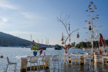 Gumusluk, Bodrum sahilindeki restoran ve bougainvillea çiçekleri. Güzel Ege Denizi yakınlarındaki Bodrum kasabasında renkli sandalyeler, masalar ve çiçekler.