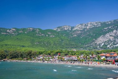 Türkiye 'nin Mugla ilçesinde Akyaka plajı, arka planda Sakar dağları ve insanlar.